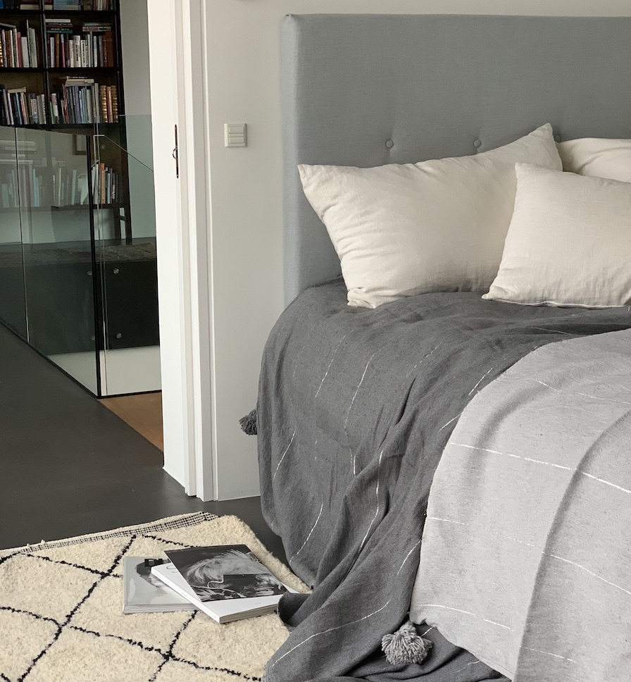 pom pom sengetæppe på seng grå